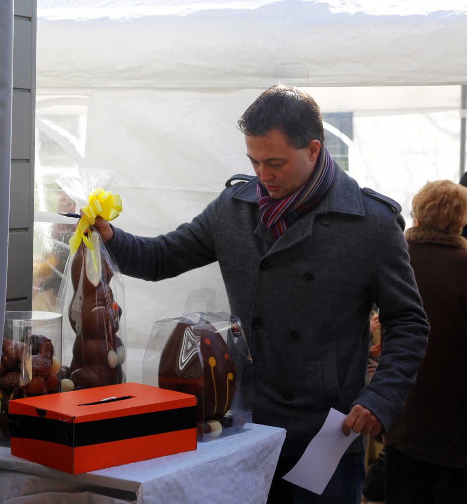 Egbert Lachaert, volksvertegenwoordiger uit Merelbeke, neemt deel aan de tombola en weegt de chocoladen stukken
