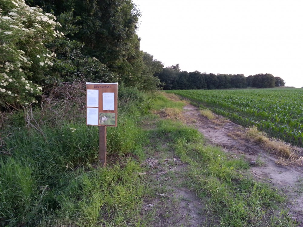 de Doopswegel waar de Rattepas in Moortsele links afdraait richting Scheldewindeke. Het bord met het verzoek van de werkgroep en de antwoorden van de gemeenten Oosterzele en Merelbeke verdween daags nadien